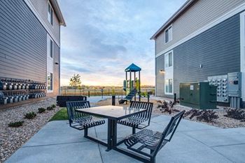 a patio with a table and chairs and a playground in the background at Connect at First Creek, Denver , 80249